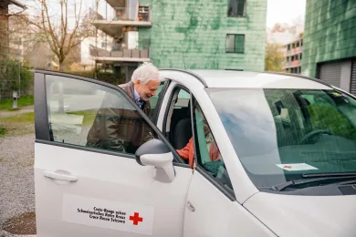 Ein freiwilliger Fahrer hilft einer Kundin aus dem Auto